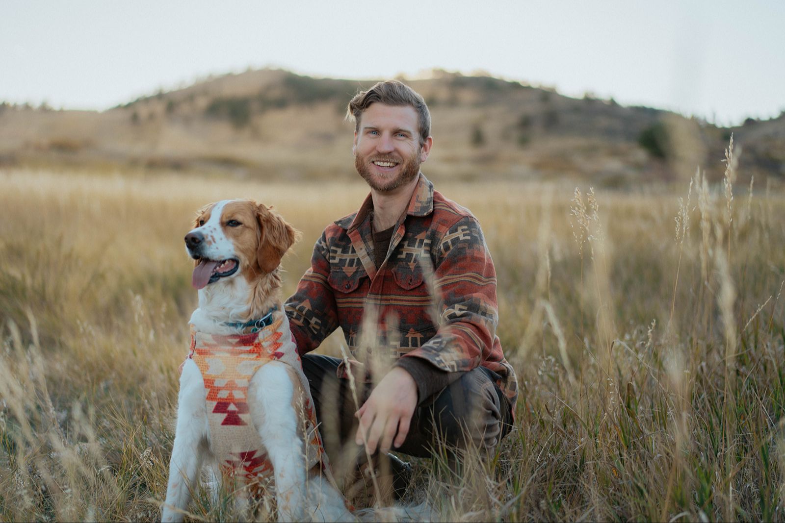 Telfer kneeling in a golden field beside his dog Rigby