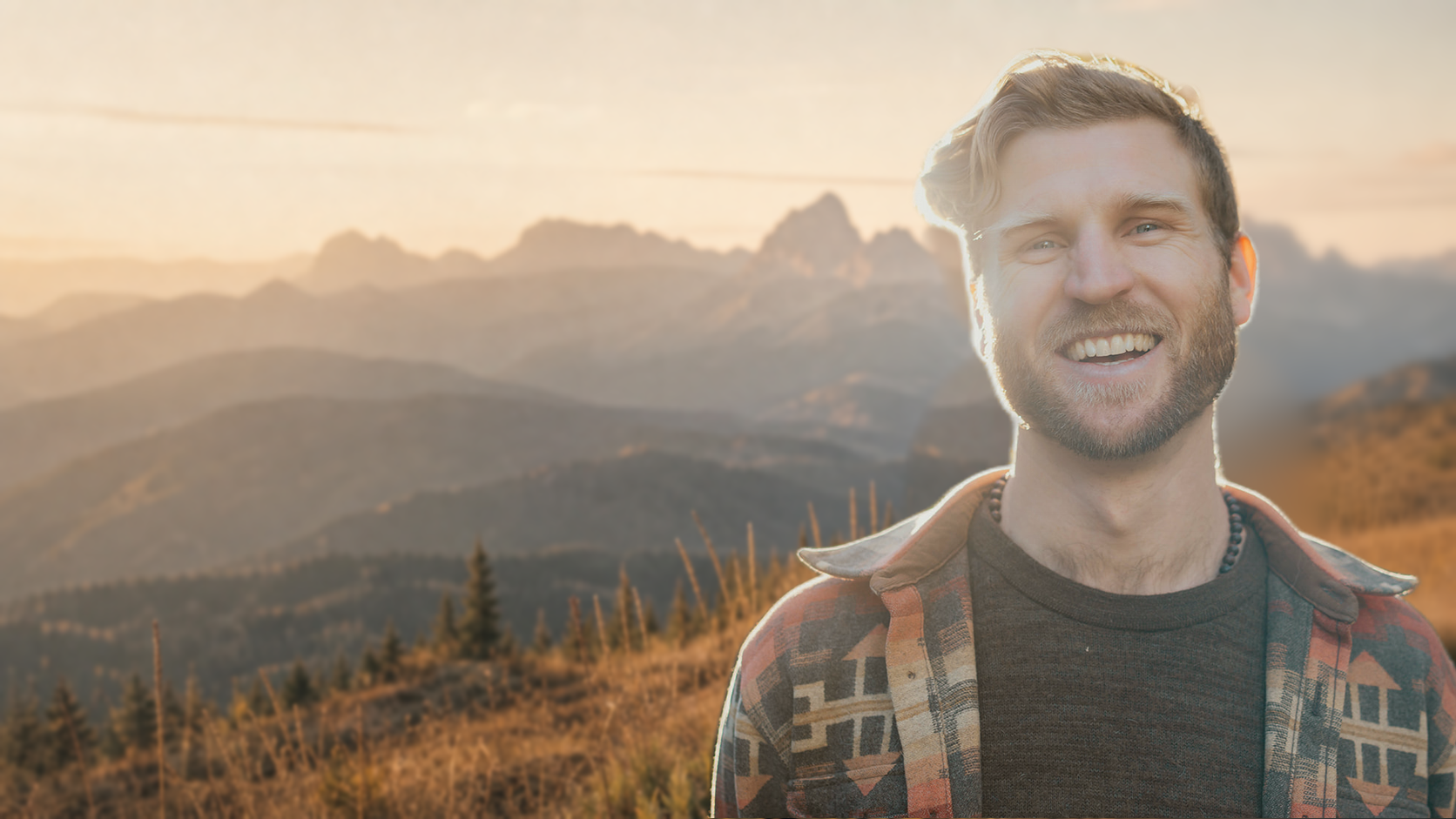 Telfer smiling in golden light, with mountain ridges behind him